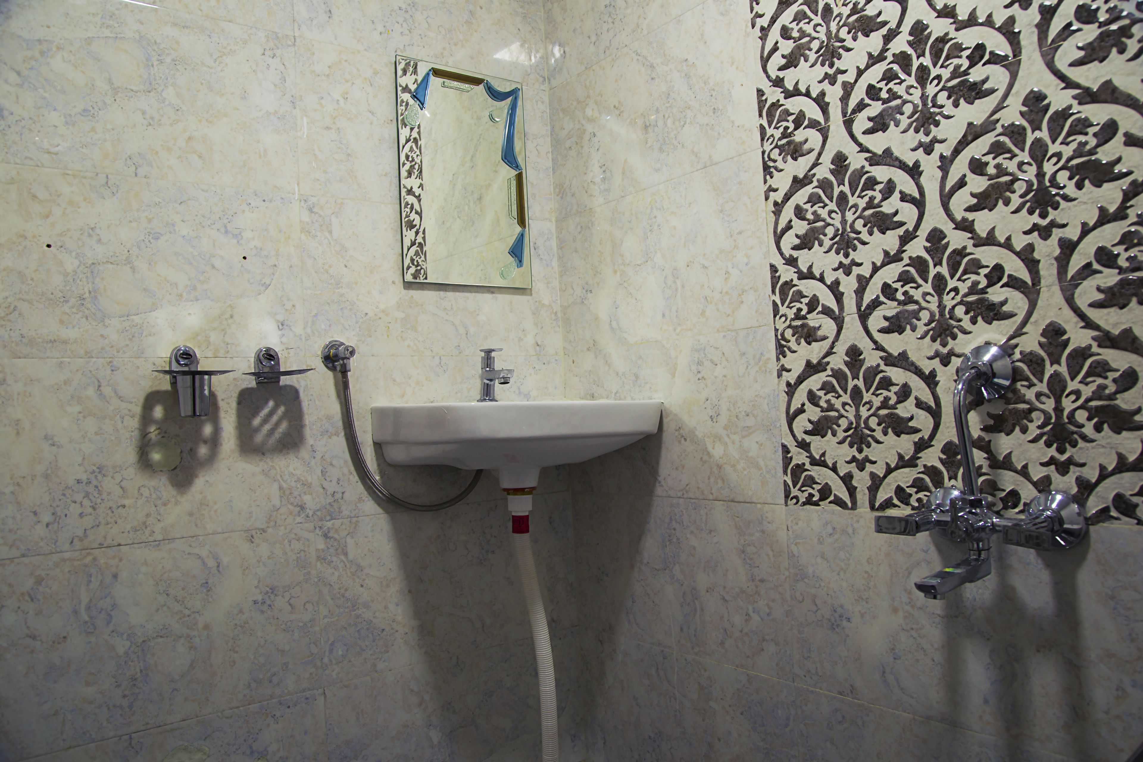 Un baño con lavamanos, espejo y azulejos con diseño.
