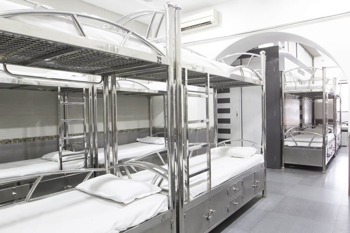 A hotel room with bunk beds, a bathroom with a shower, and a view of the city.