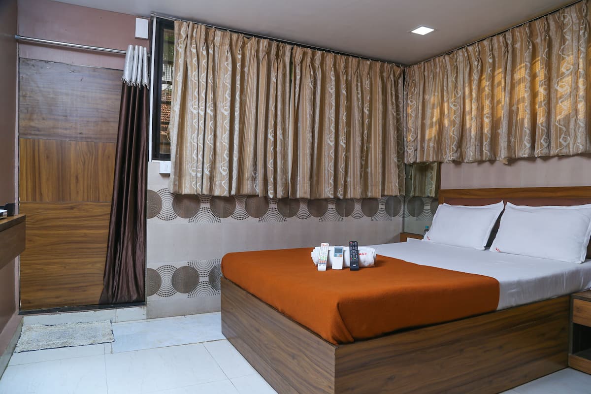 A hotel room with a wooden bed, a brown blanket, and a window with patterned curtains.