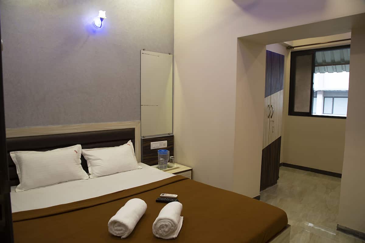 A hotel room with a bed, a nightstand, a remote control, and towels.