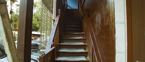 A narrow staircase with wooden steps and metal railings, leading to an upper floor.