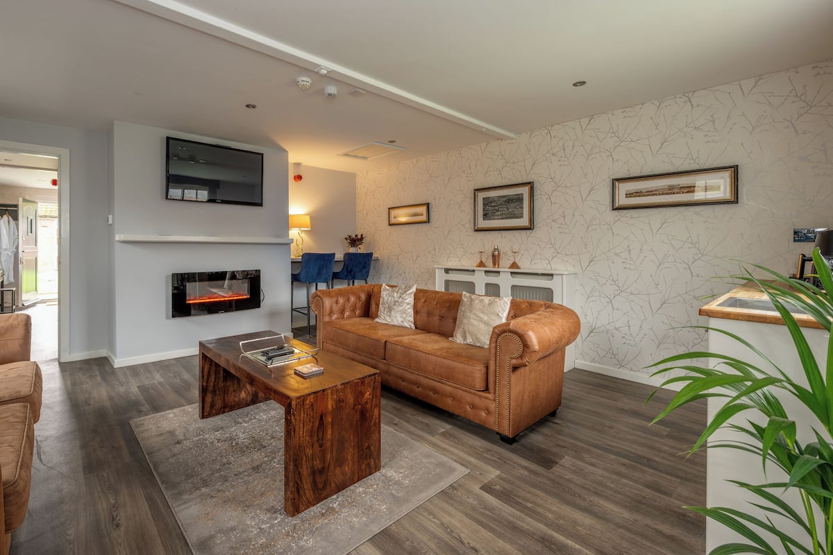 Una sala de estar moderna con un sofá de cuero, una mesa de centro de madera y una chimenea.