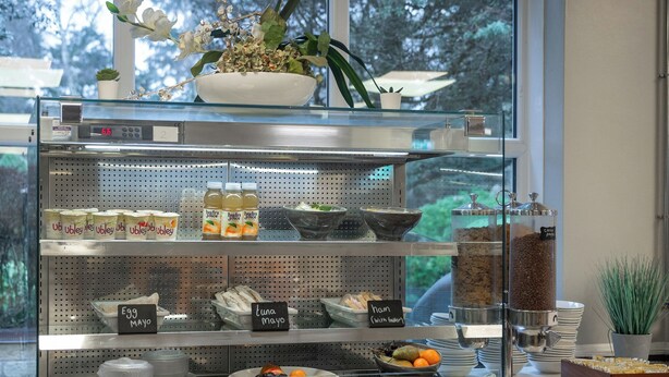 A breakfast bar with various food items and condiments, including eggs, mayo, and a coffee machine. - Stableside at York Racecourse (York)