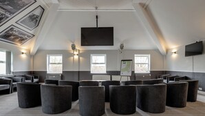 A conference room with a large screen, multiple seating areas, and a projector. - Stableside at York Racecourse (York)