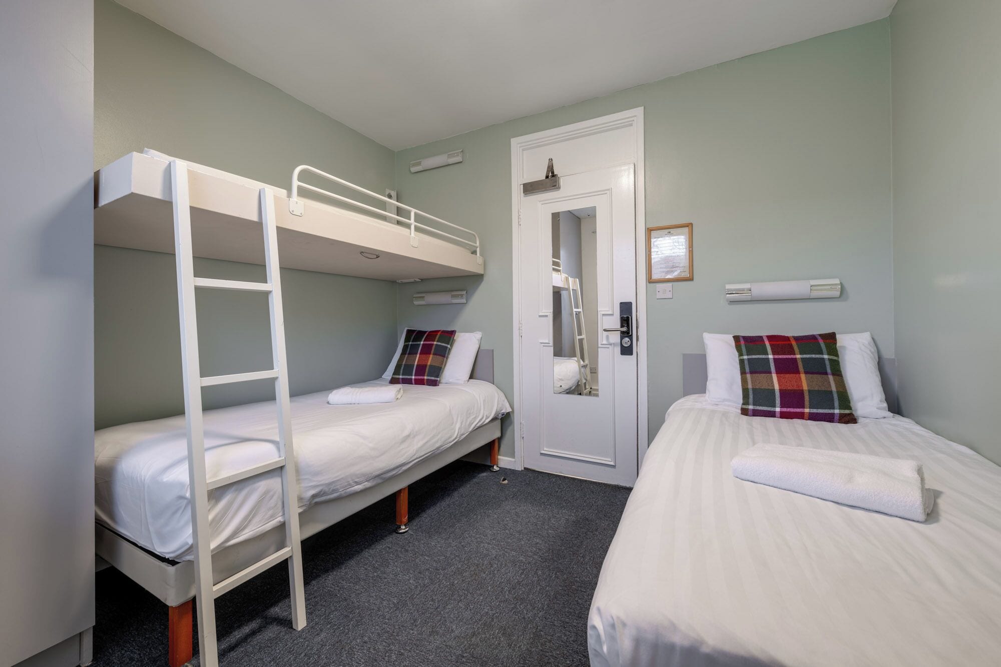 A room with bunk beds, a door, and a small window.