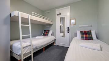 A room with bunk beds, a door, and a small window.