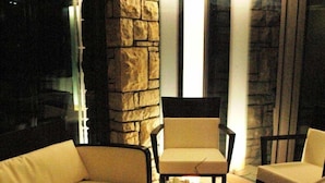 Una sala de estar moderna con una pared de acento de piedra, una mesa de centro de vidrio y dos sillones.