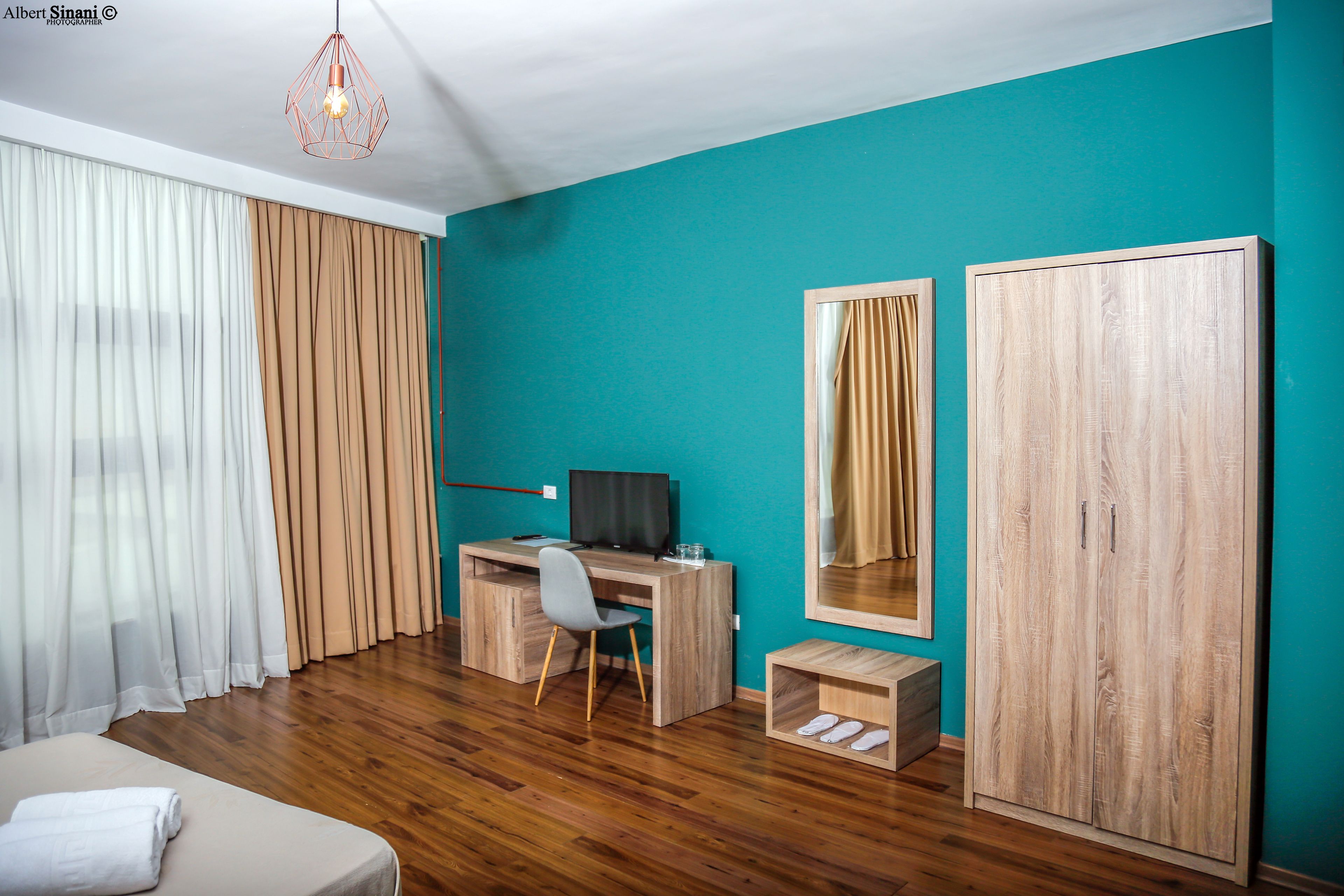 A room with a wooden desk, a chair, a bed, a wardrobe, and a mirror.
