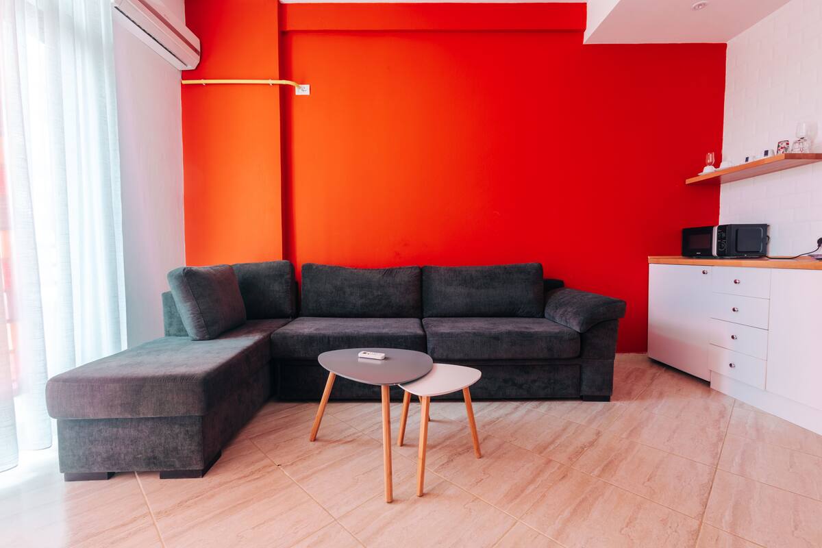 A modern living room with a sectional sofa, a small round table, and a white cabinet with a microwave.