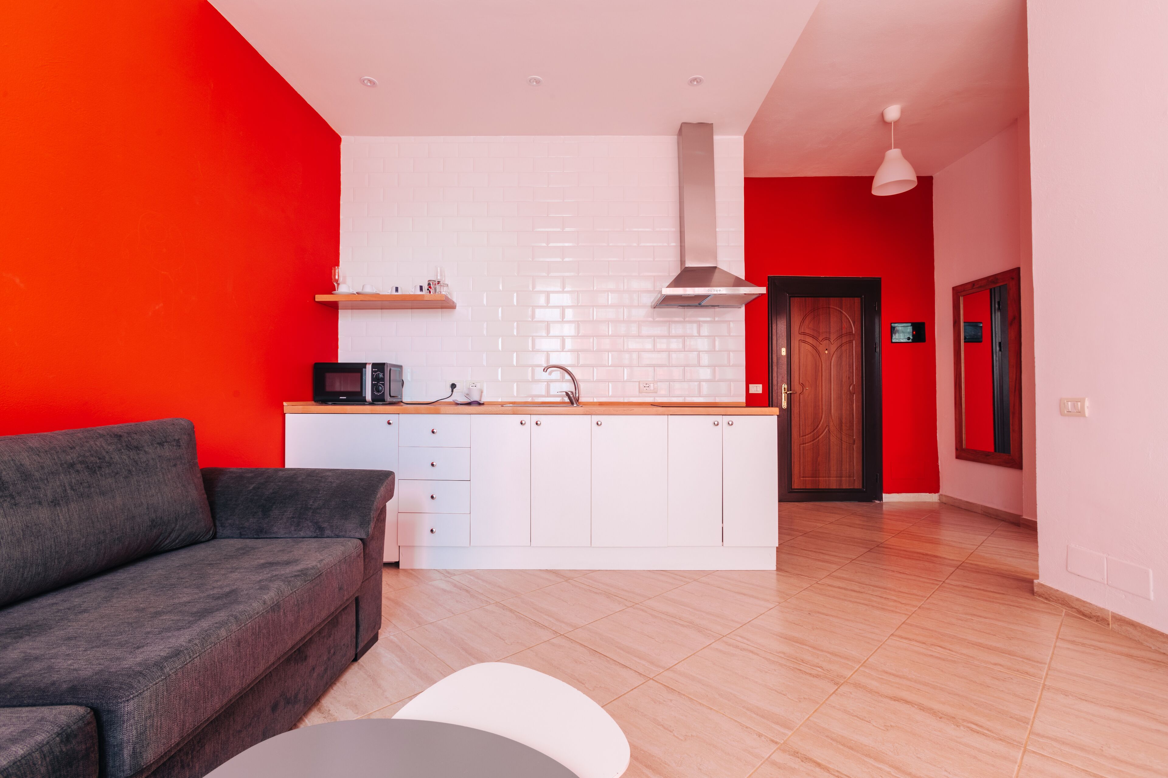 Una cocina moderna con armarios blancos, encimera de madera y microondas integrado.