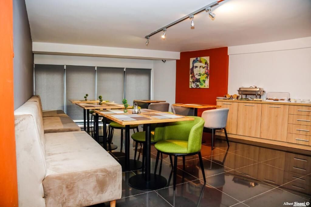 Un comedor moderno con un banco largo, varias mesas y sillas.