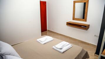 Una habitación de hotel con una cama, un estante de madera y un espejo en la pared.
