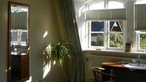 A room with a large window, a radiator, a table with a bottle, and a plant. - Faehrhaus Niederkleveez (Bösdorf)