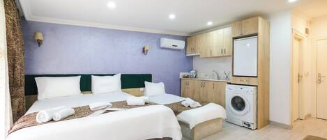 A hotel room with two beds, a washing machine, and a kitchenette.