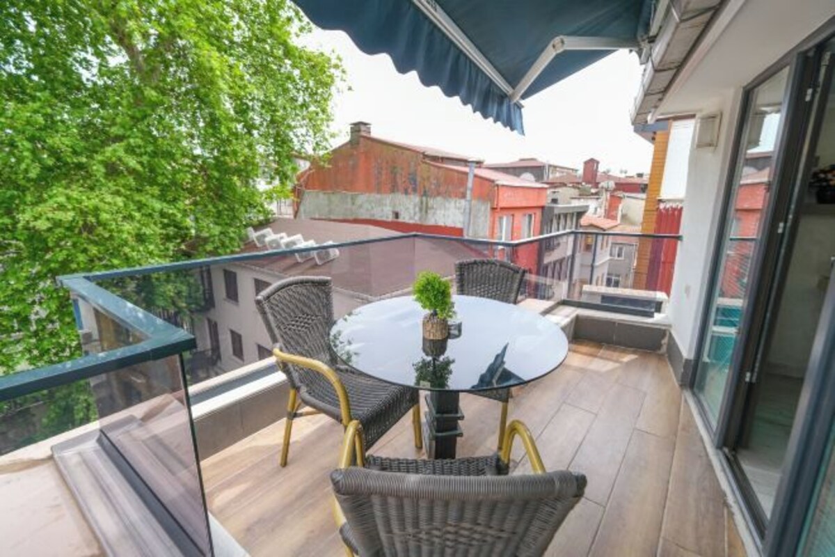 A balcony with wicker chairs, a glass table, and a potted plant.