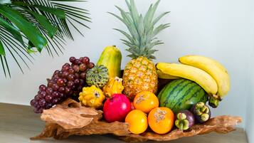 Una bandeja de madera con una variedad de frutas, incluyendo uvas, plátanos, piña y sandía.