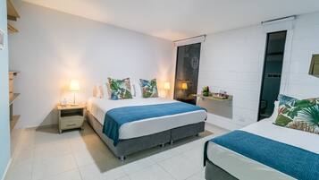 Et moderne hotelværelse med to senge, et lille skrivebord og et vindue.