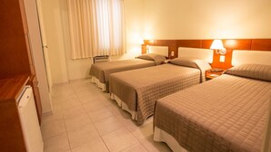 A hotel room with two beds, a wooden cabinet, a radiator, and a window with curtains. - Hotel Ipanema de Sorocaba (Sorocaba)