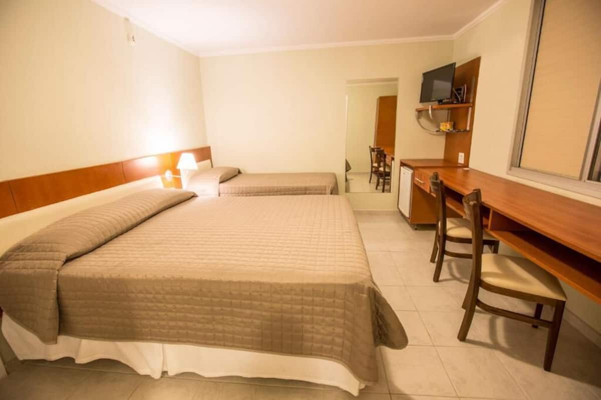 Ein Hotelzimmer mit zwei Betten, einem Schreibtisch und einem Stuhl.