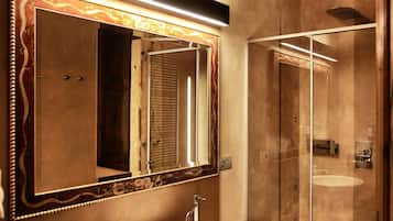 A bathroom with a large mirror, a wooden vanity, a white sink, and a glass shower enclosure.