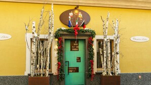 A hotel entrance with a green door, decorated with Christmas garlands and a sign above stating "Le Creve Charmant". - Le Reve Charmant (Aosta)