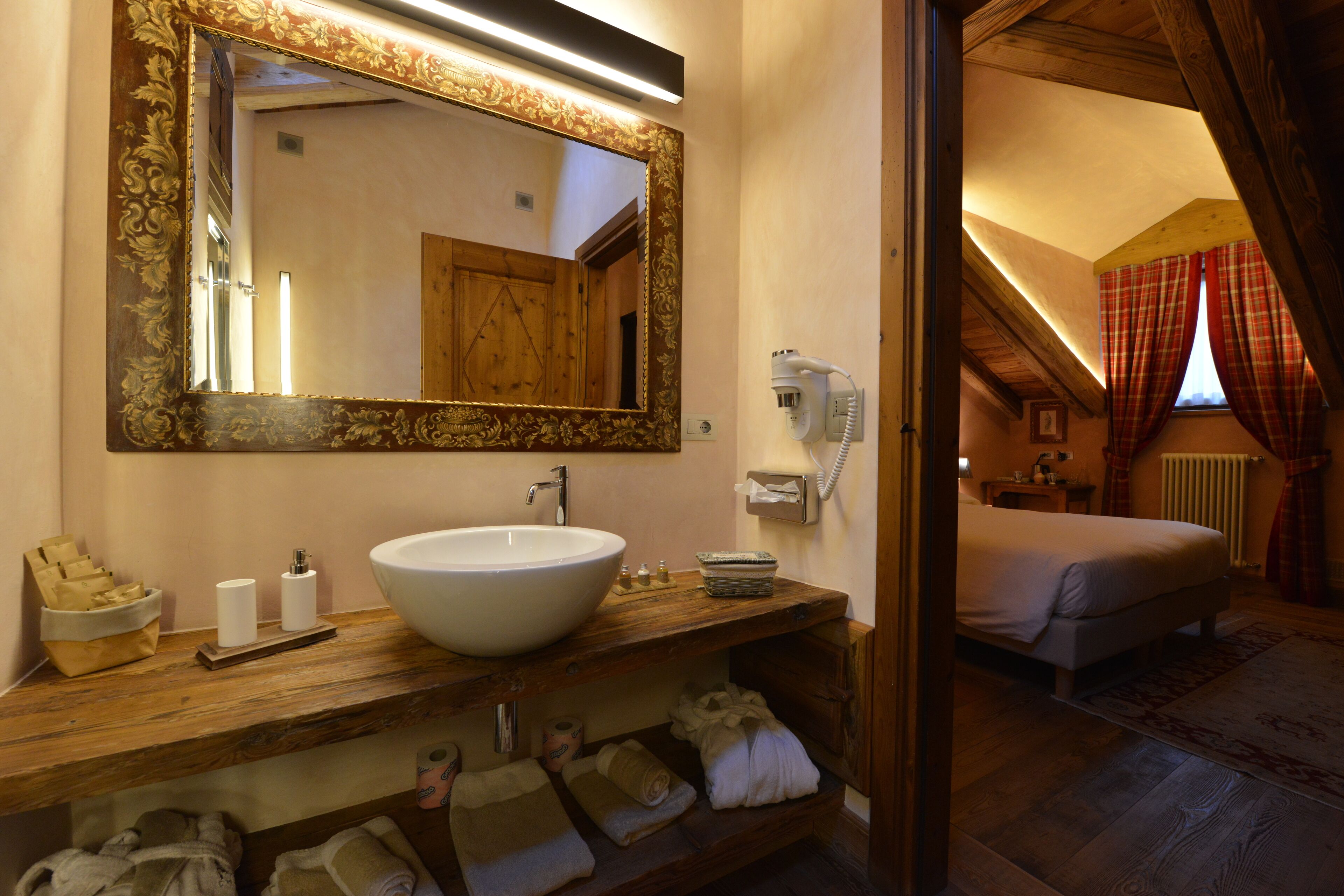 Un baño con un espejo grande, un lavamanos y un mueble de tocador de madera con toallas.