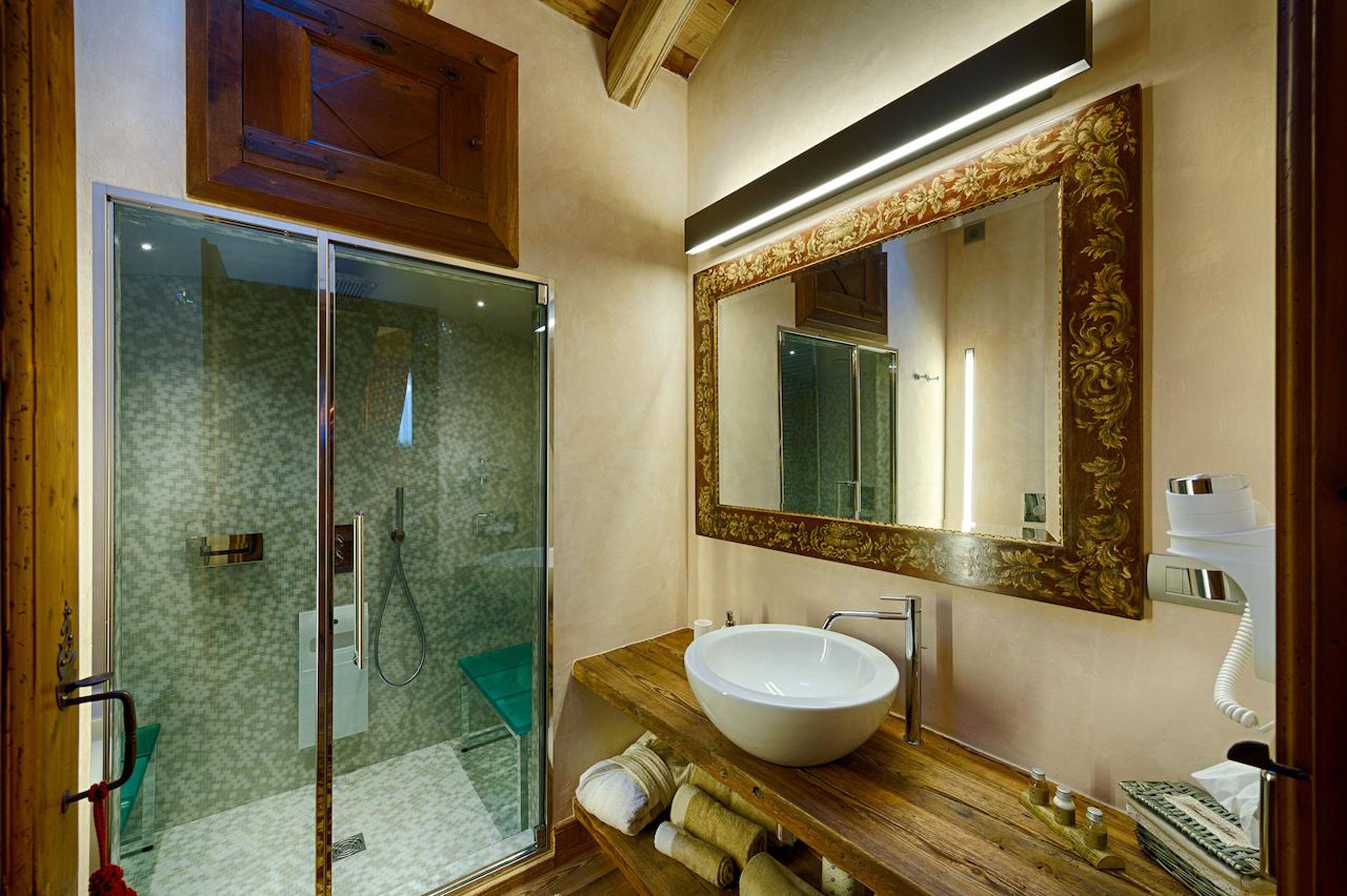 A modern bathroom with a glass shower enclosure, a wooden vanity with a large mirror, and a white sink.