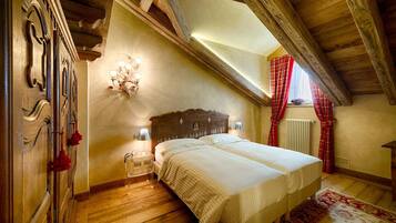 Un dormitorio con techo de madera, una cama, una mesita de noche, una lámpara de pared y una ventana con cortinas rojas.