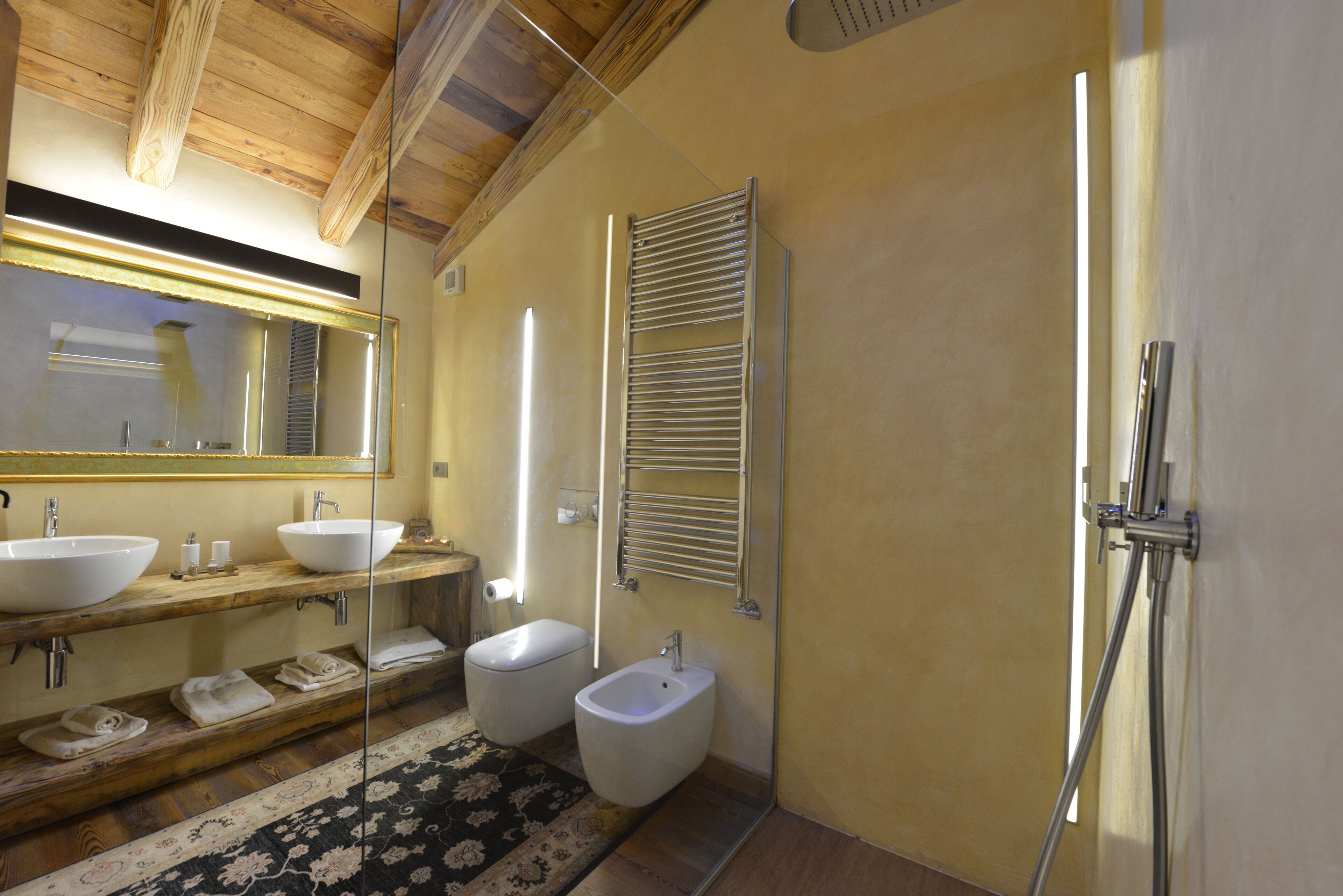 Un baño moderno con dos lavamanos, un bidé, una ducha y un espejo.