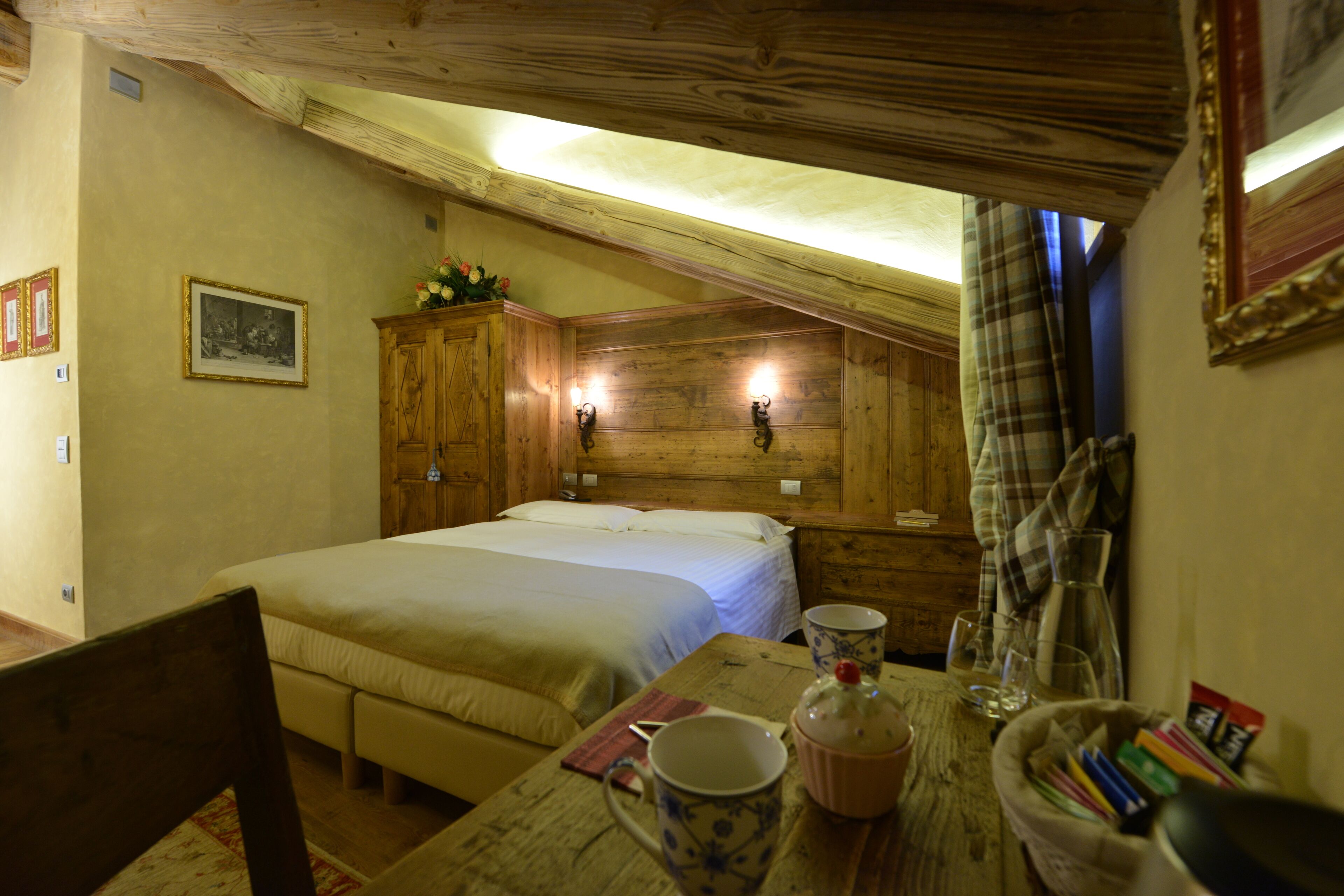 Un dormitorio acogedor con dos camas, cabecero de madera, una mesa con una taza y libros, y una ventana con cortinas.