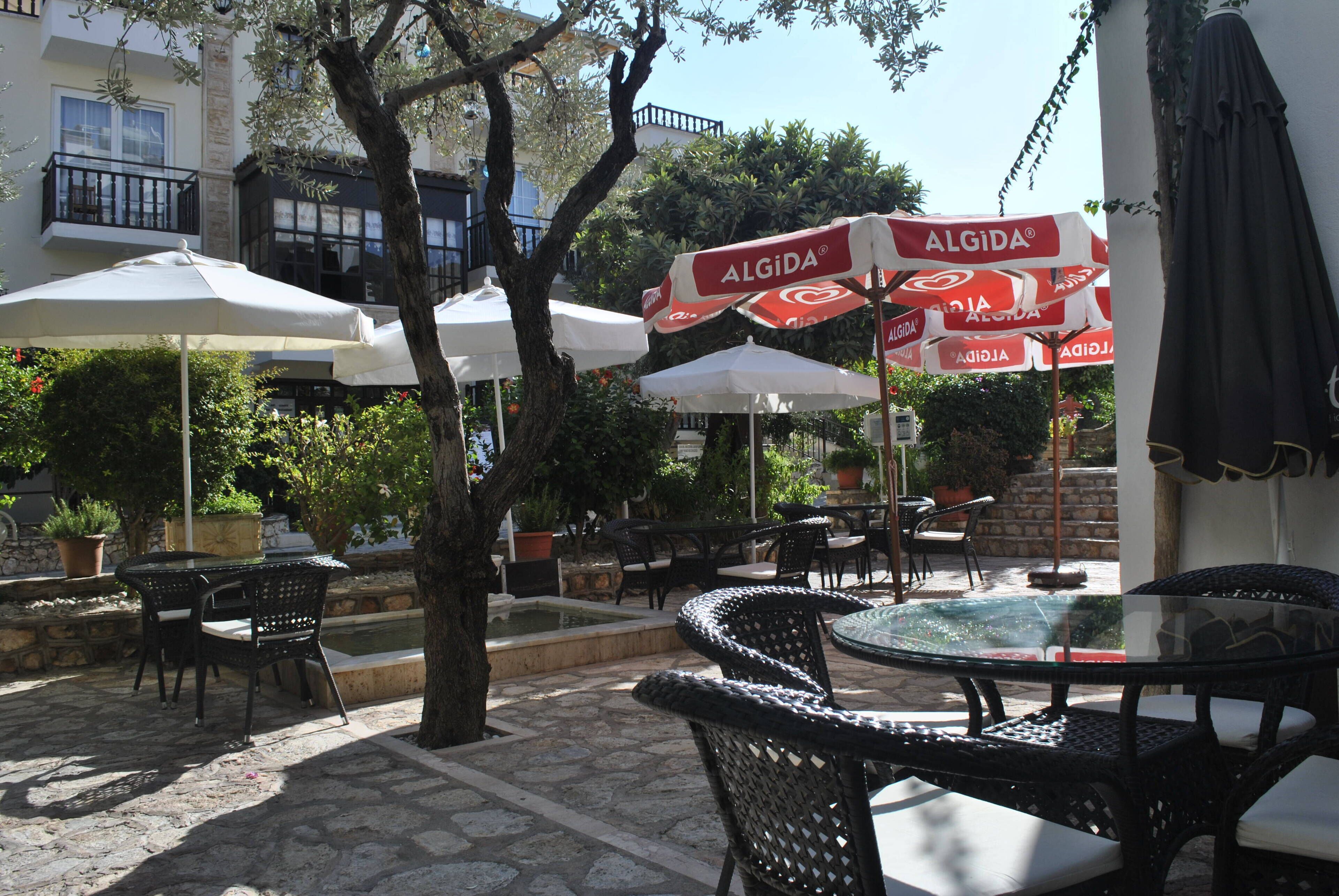 An outdoor patio with wicker furniture, umbrellas, and a fountain.