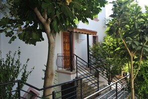 A white building with a wooden door, a stone staircase, and a metal railing. - Hotel Dionysia (Kas)