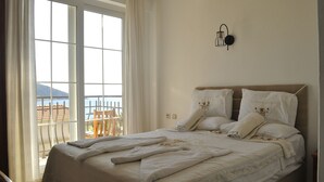 A bedroom with a large bed, a view of the outdoors, and a wall-mounted light fixture. - Hotel Dionysia (Kas)