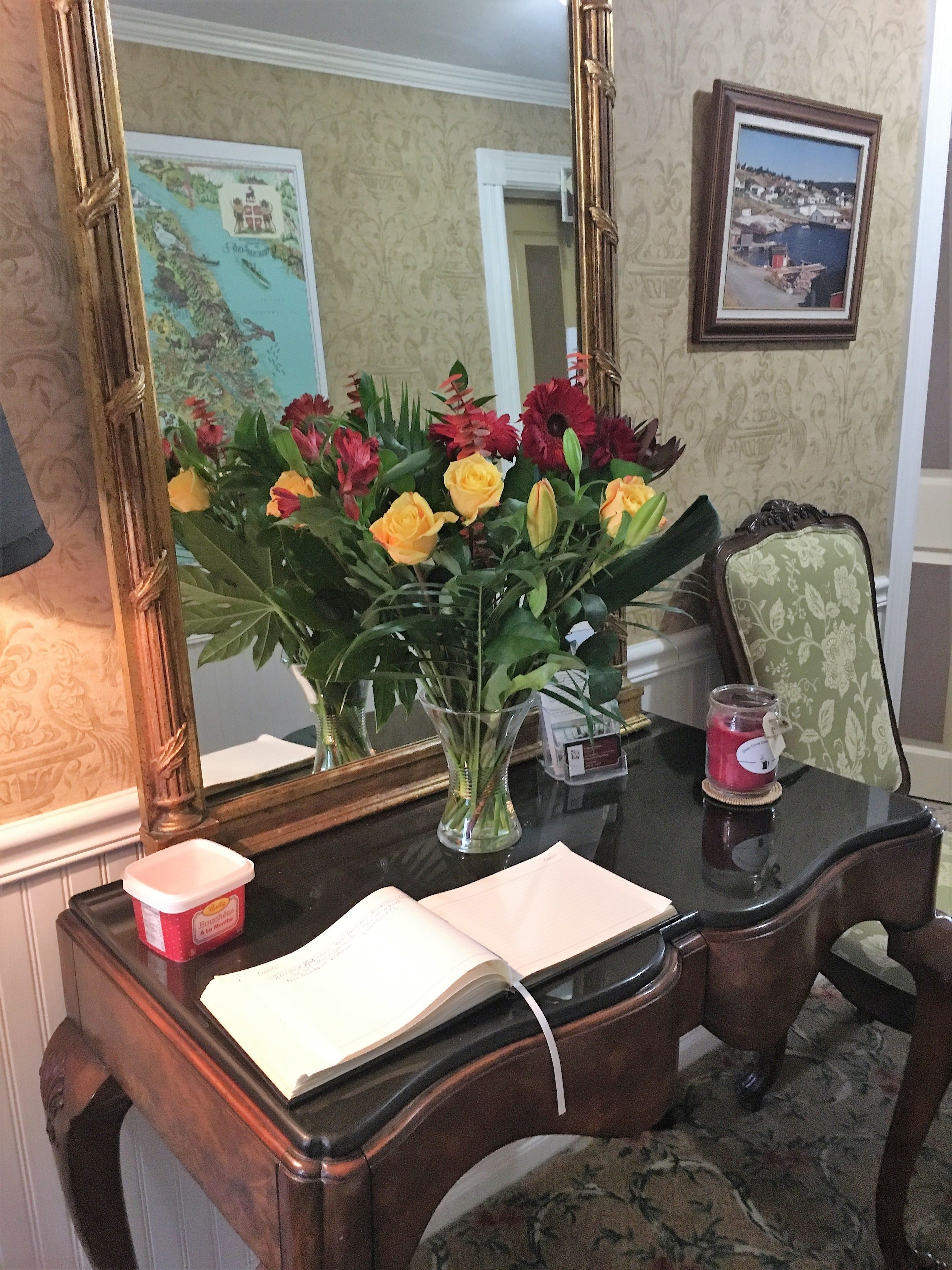 A desk with a vase of flowers, a candle, and a book.