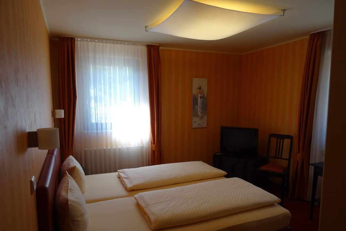 A hotel room with two beds, a television, and a chair.