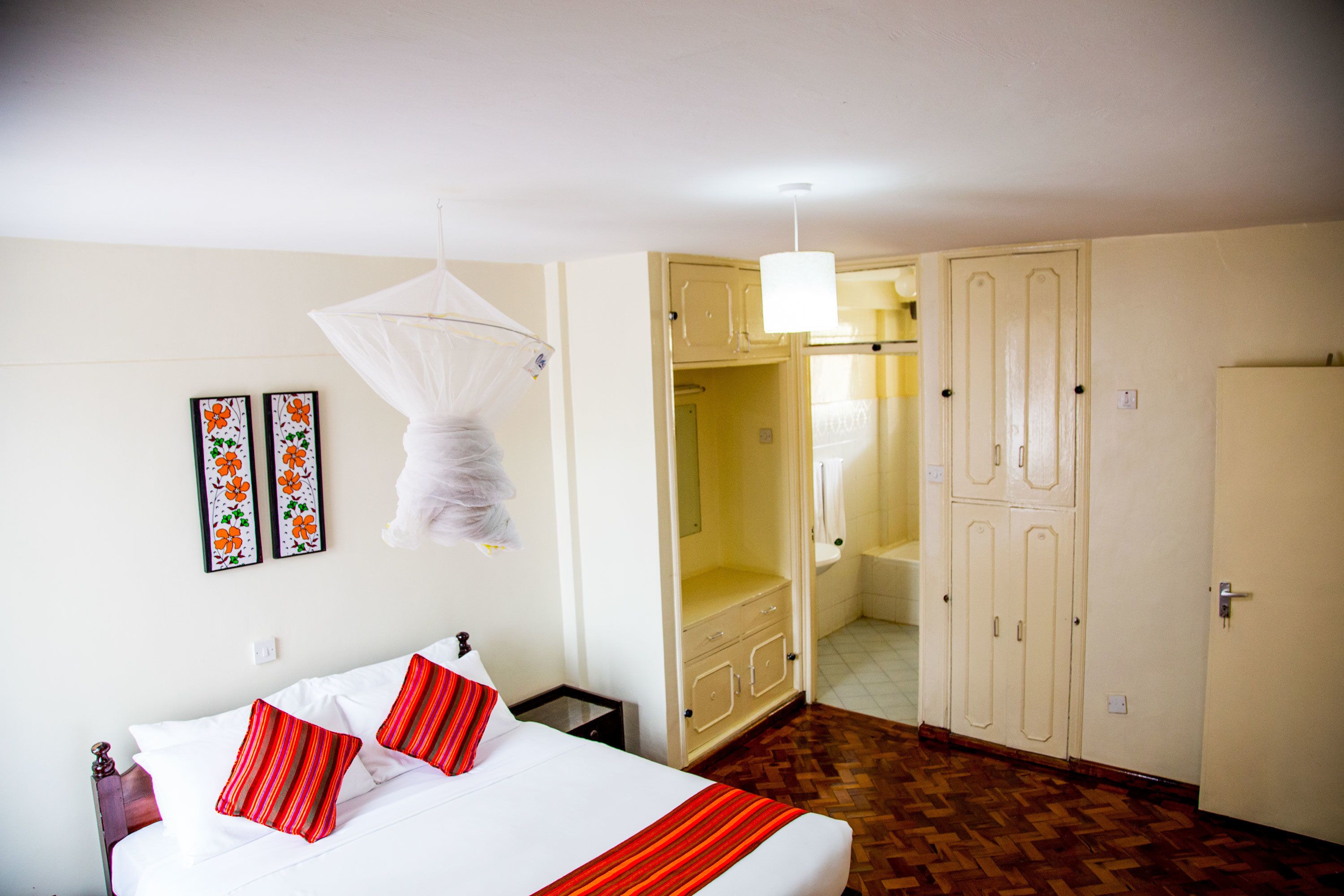 A hotel room with a bed, a wardrobe, and a mirror.
