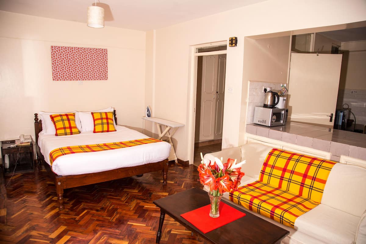A hotel room with a bed, a sofa, a coffee machine, and a mirror.
