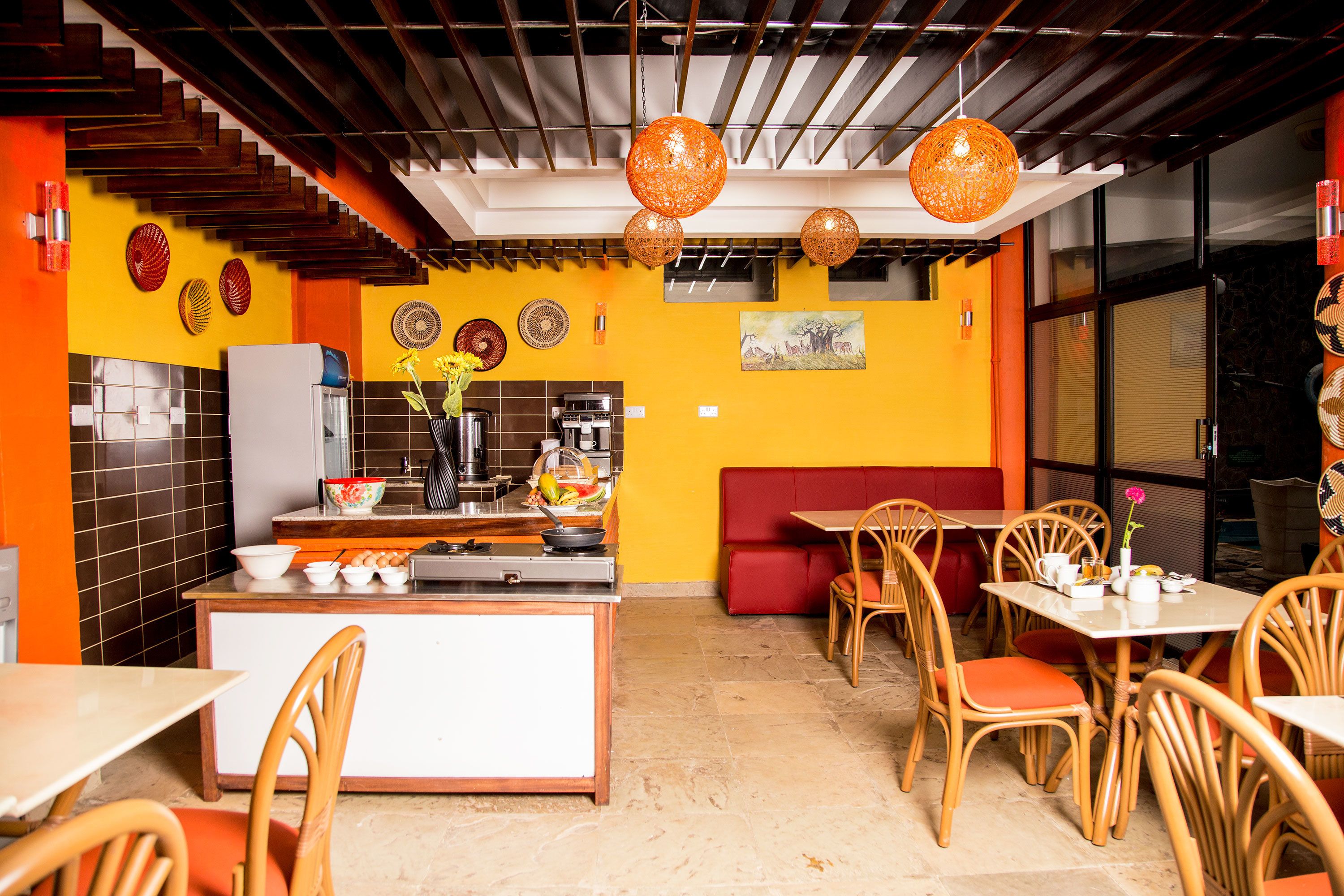 A restaurant interior with a kitchen area, dining tables, and chairs.