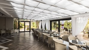 Un espacio interior amplio con mobiliario de mimbre, ventanas grandes y un suelo con patrón de espiga.
