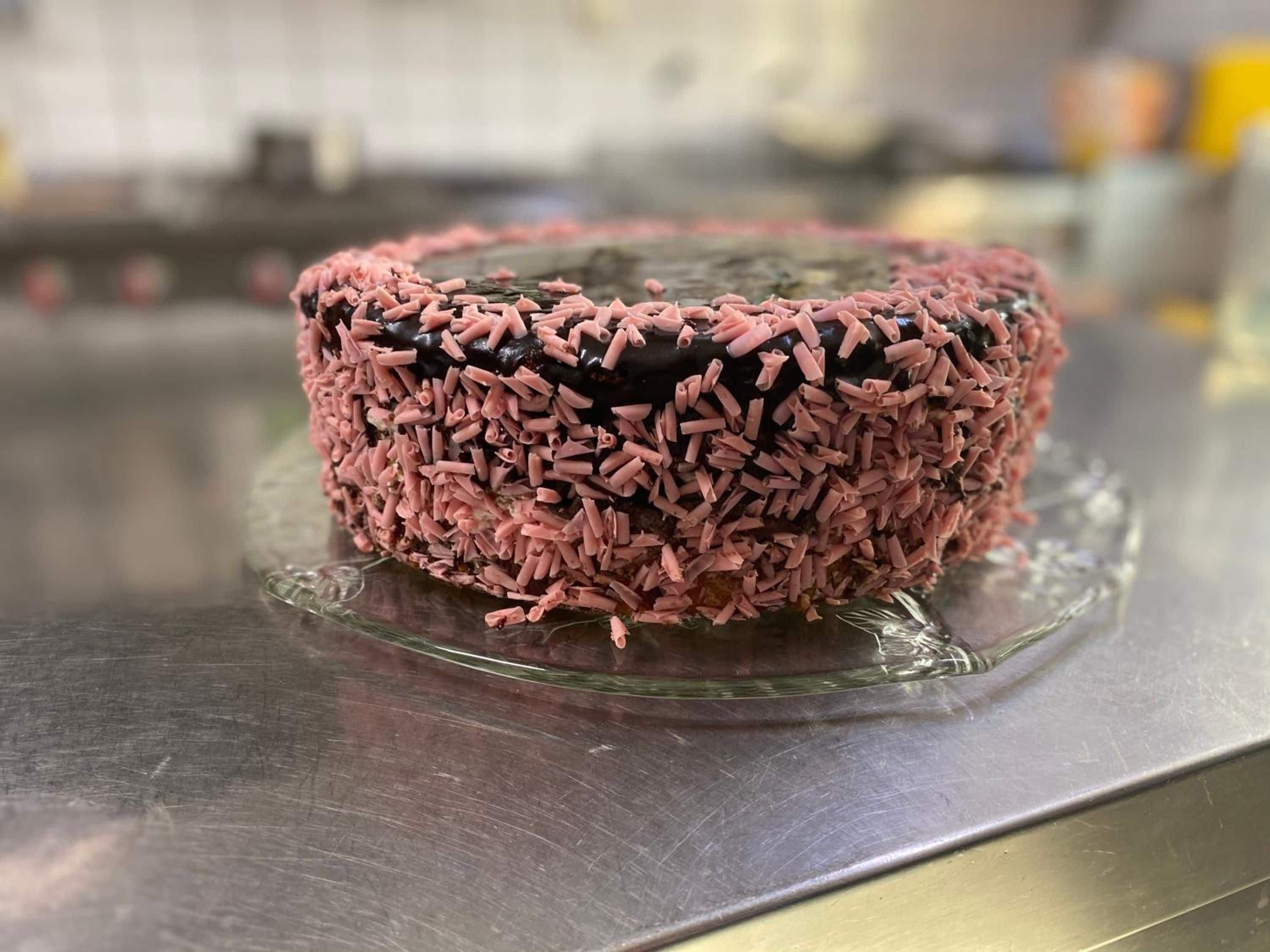 A cake with pink sprinkles on a clear glass plate.