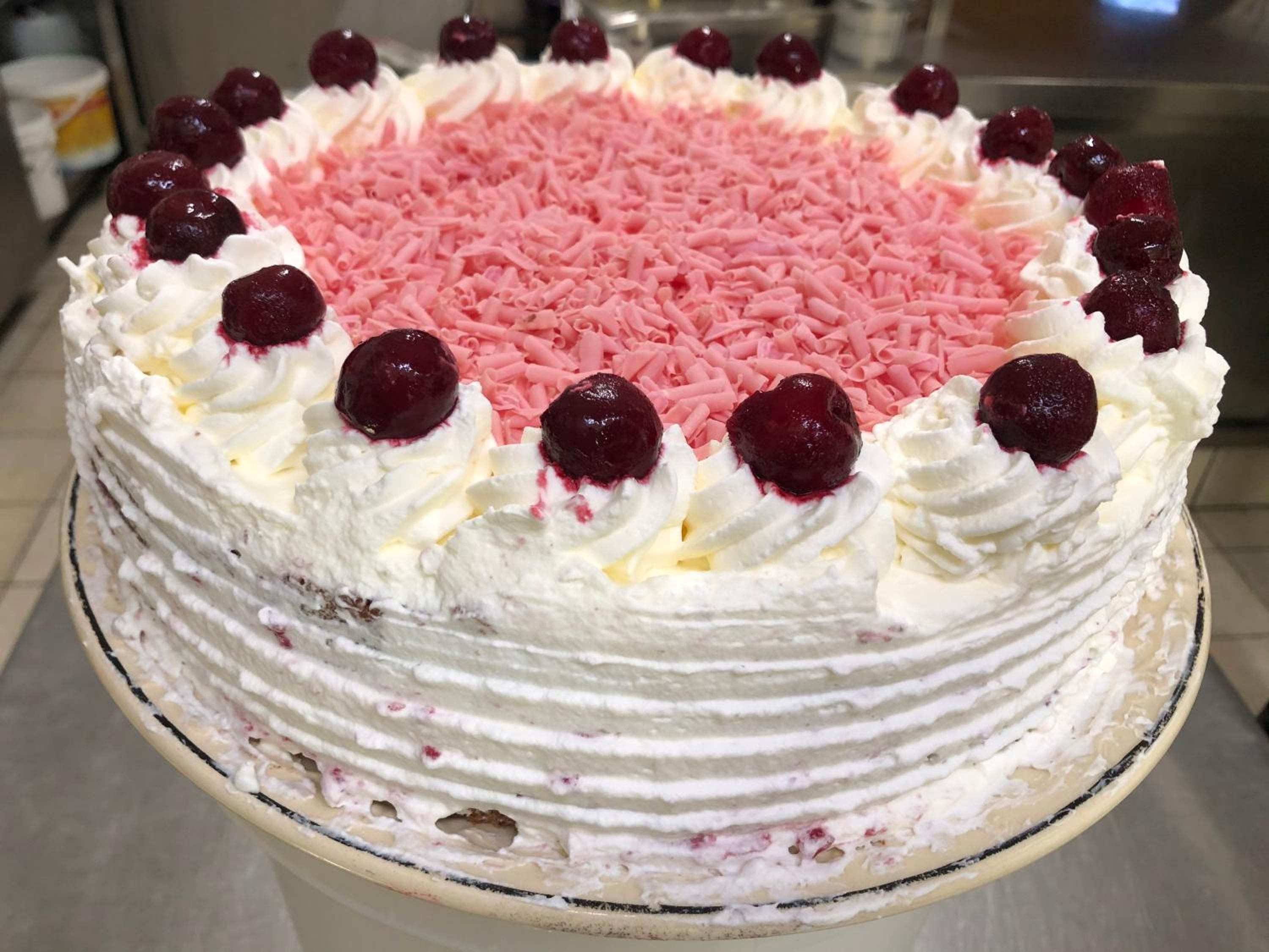 A cake with pink sprinkles and cherries on top.