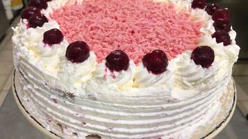 A cake with pink sprinkles and cherries on top.