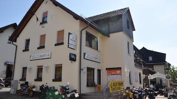 A building with multiple signs for a hotel, cafe, and restaurant. There are motorcycles parked in front.