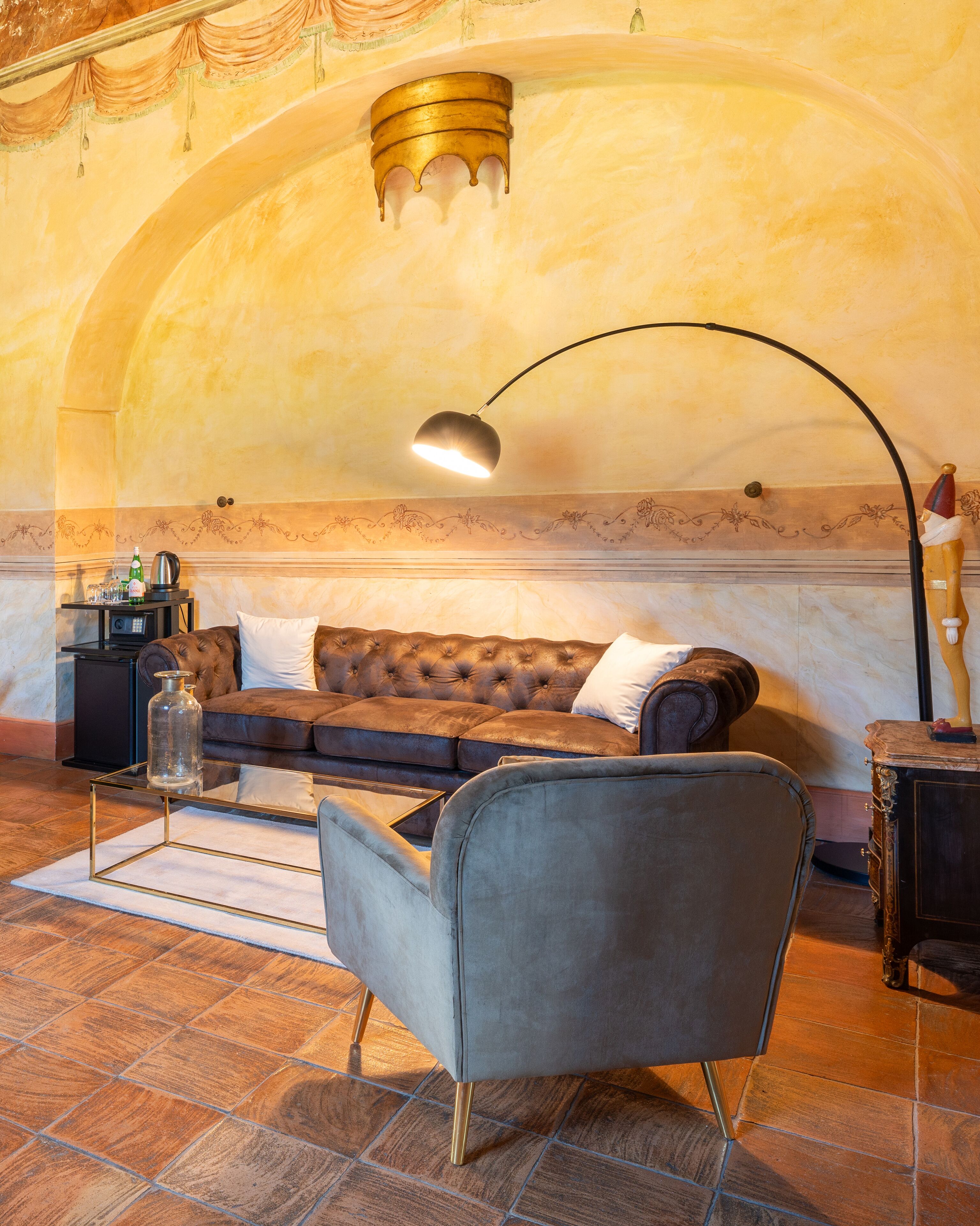 A cozy living room with a tufted sofa, a glass coffee table, and a modern floor lamp.