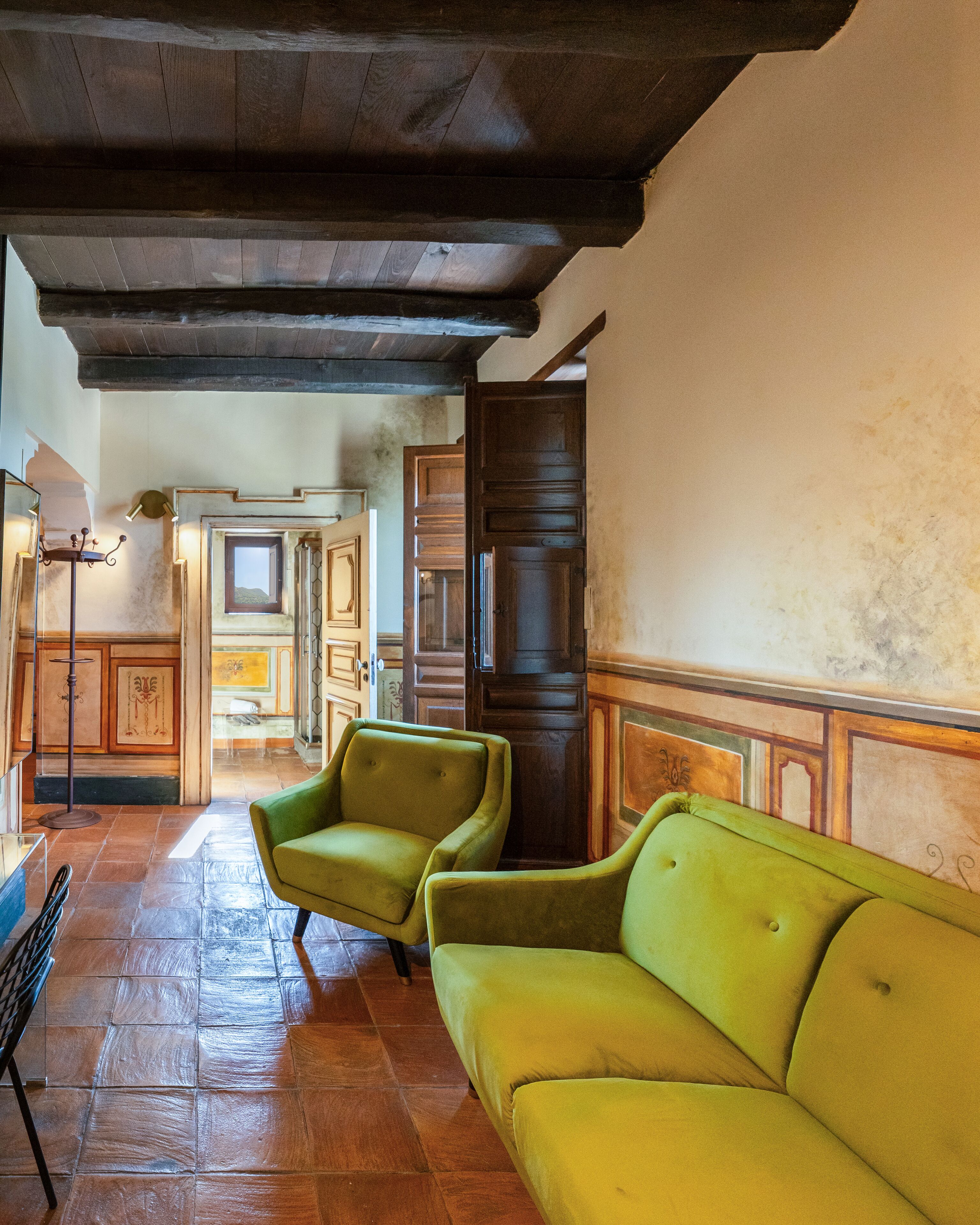 Una habitación con techo de madera, sofá verde y suelo de baldosas.