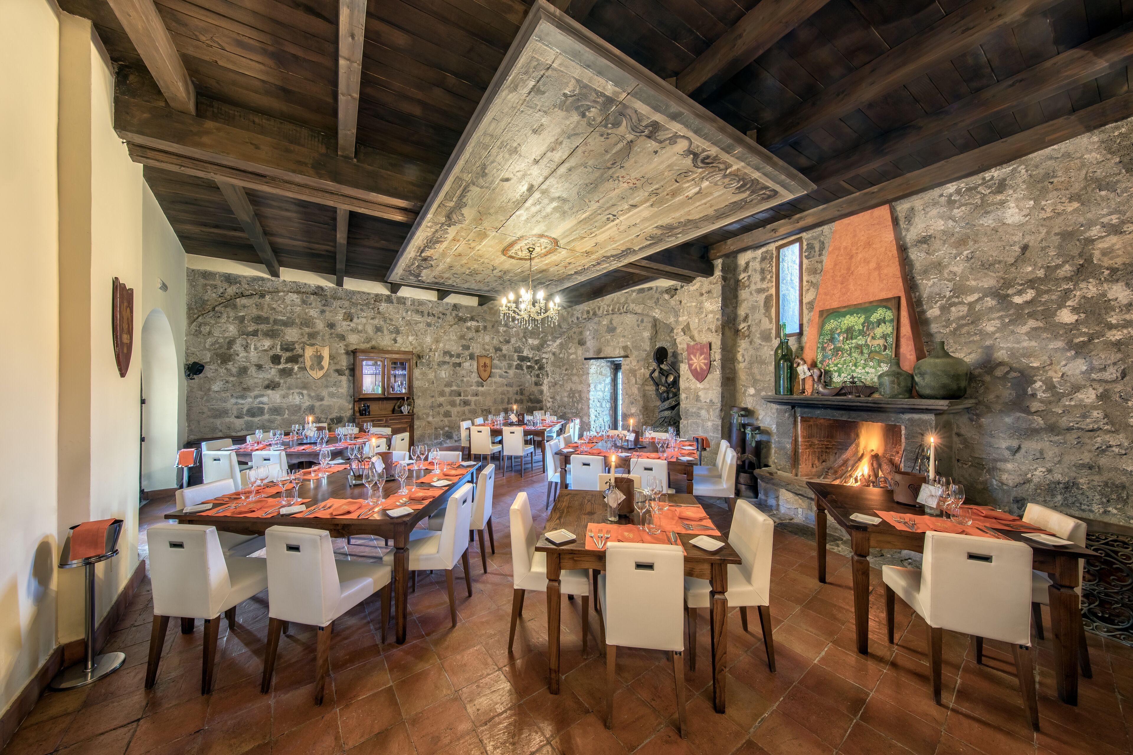 Ein Restaurant mit mehreren gedeckten Tischen für Gäste, Steinwänden und einem Kamin.