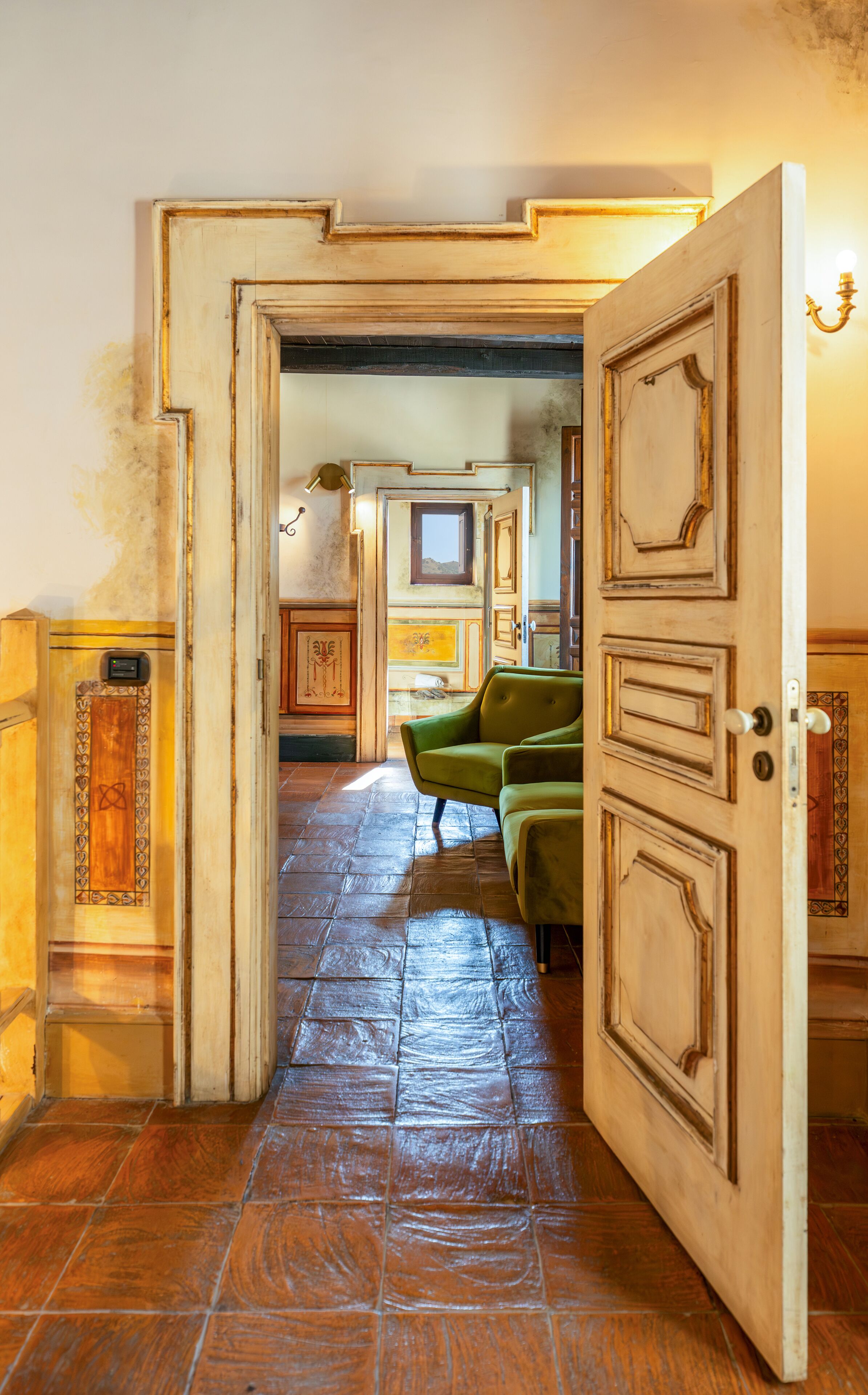 A hallway with a wooden door, a green sofa, and a tiled floor.