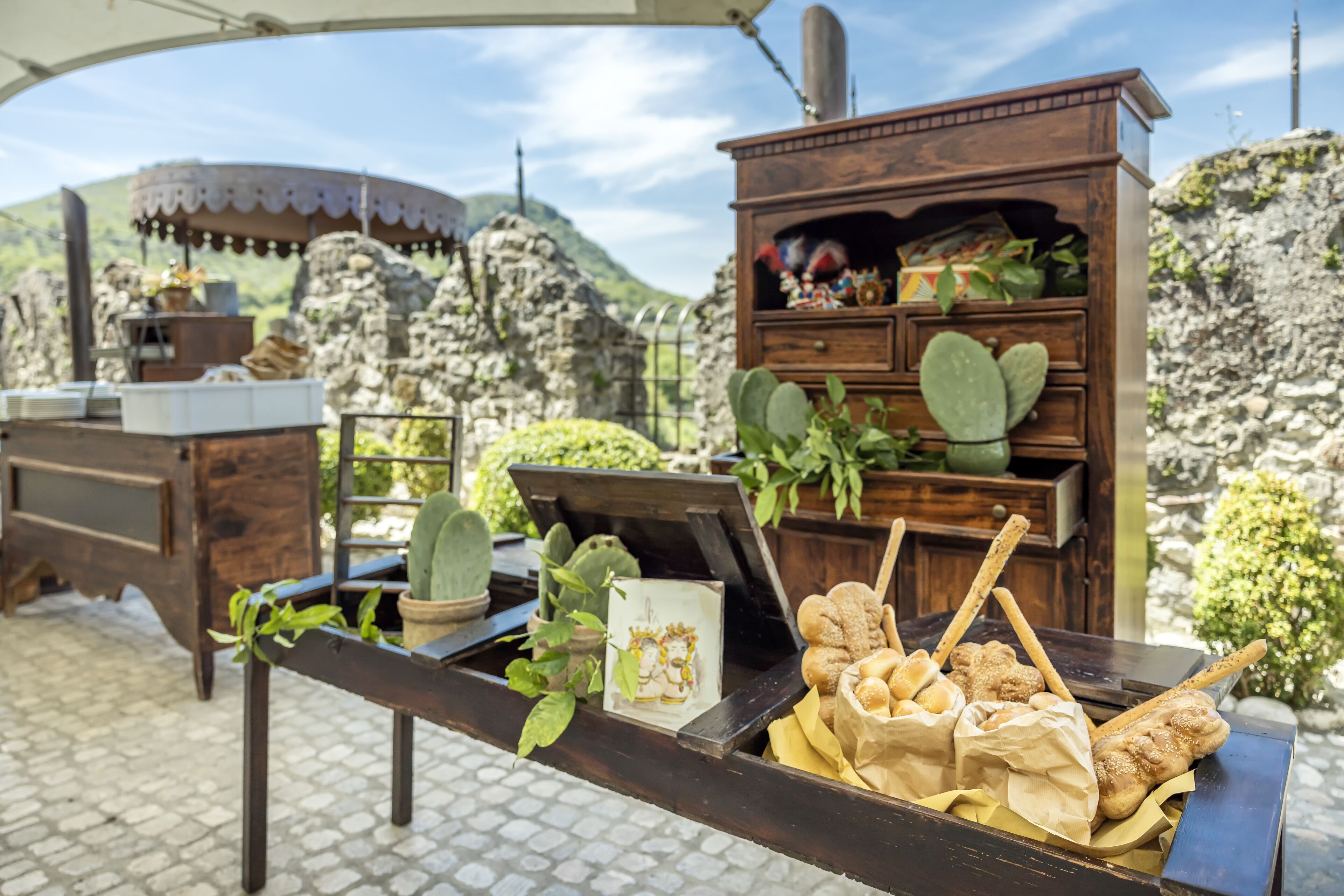 Um ambiente de refeições ao ar livre rústico, com uma mesa de madeira, um armário de madeira com plantas e um belíssimo cenário montanhoso.