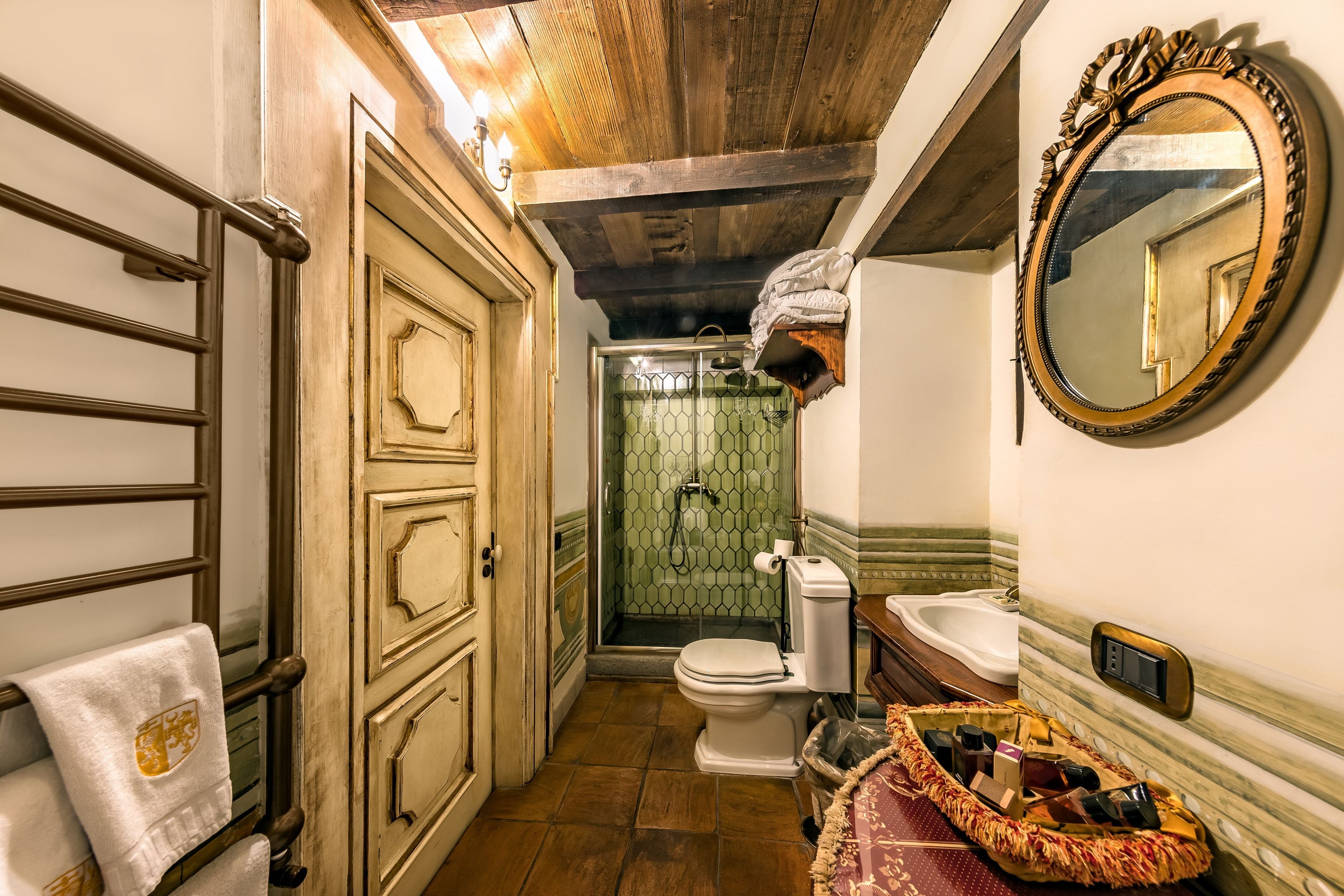 Une salle de bain avec un plafond en bois, une douche avec une porte en verre, des toilettes, un lavabo et un miroir.