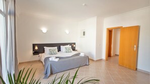 Een slaapkamer met een bed, nachtkastjes, een klein raam en een deur.